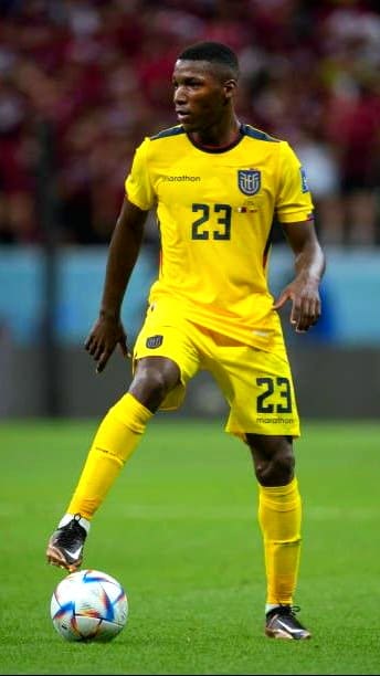 A soccer player in a yellow jersey with number 23 controls the ball on a field during a match, with blurred spectators in the background—a moment you can catch live through IPTV Netherland.